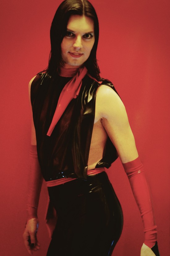 A black and red latex jumpsuit with a draped top and two red bows. Designed by Rubberik.